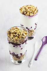 Useful dessert of granola, yogurt and blueberry in glass on a wh