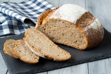 Rye round bread on stone cutting board with napkin on wooden background