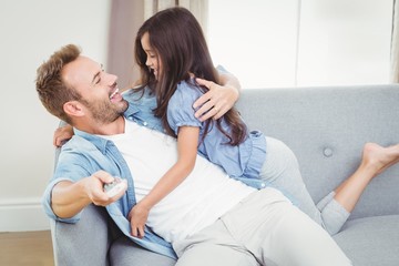Smiling daughter hugging father sitting on sofa 