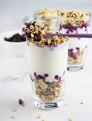 Useful dessert of granola, yogurt and blueberry in glass on a wh