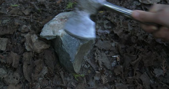 Detail of woman's hands sharpening axe on stone during camping
