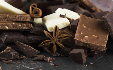 Pieces of various chocolate with spices on a dark background