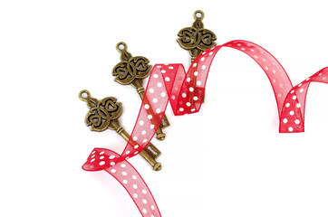 Decorative bronze key of different shape with red ribbon on white background