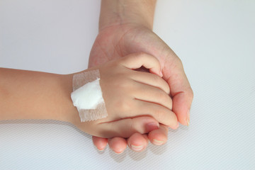 Children hand with bandage on her mother hand