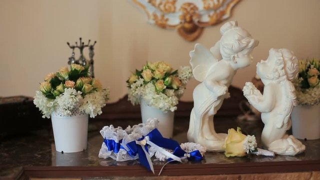 White ceramic sitting angels kissing on flowers background