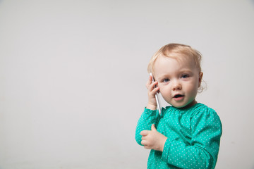 Cute little baby is talking on cell phone, isolated over white