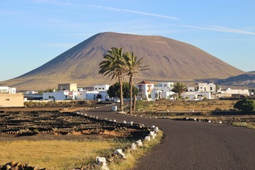 Village and volcano in early morning light. Lanzarote, San Canary Islands, Spain. In the inland near San Bartolome and La Geria. - obrazy, fototapety, plakaty