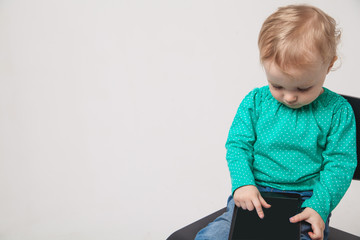 Infant child baby girl toddler sitting and typing digital tablet mobile computer isolated on a white background