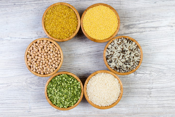 Set of cereals, peas, rice, millet, chickpeas sprinkled in bamboo bowls on wooden background