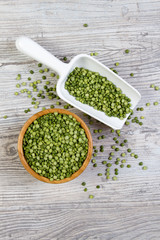 Peas in bamboo bowl with a shovel on a white wooden background