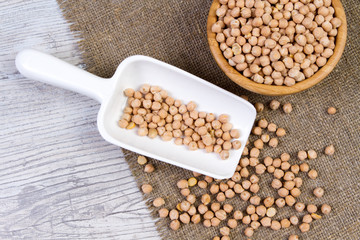 Walnut chickpeas in a bamboo bowl with a shovel on a white wooden background