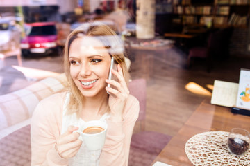 Woman in cafe drinking coffee, making a phone call