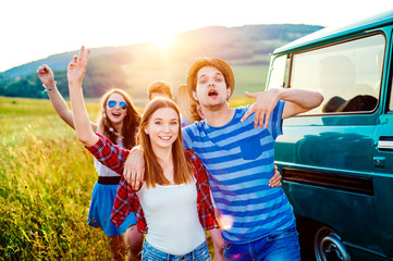 Fototapeta na wymiar Young frieds with campervan, green nature and blue sky