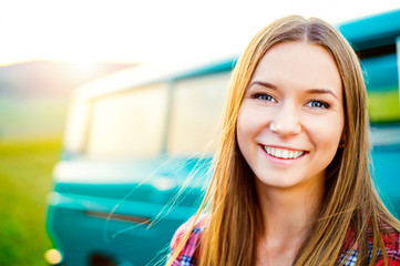 Teenage girl smiling against green campervan outside in nature