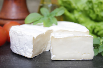 Brie cheese. Camembert cheese. Fresh Brie or Camembert cheese with basil leaves. Italian, French and Mediterranean ingredients.