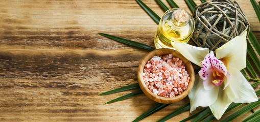 Spa orchid setting with body oil and salt on wooden background