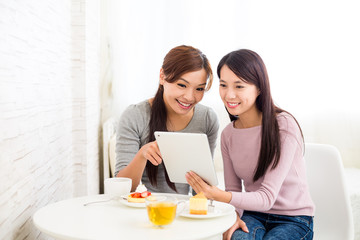 Two woman use of tablet together inside coffee shop