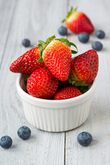 Bowl with strawberry and blueberries on wooden background