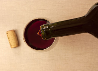 Red wine poured from bottle into glass on blurred background