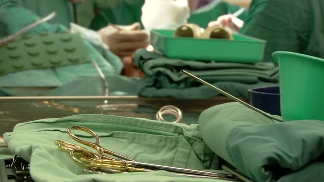 Hospital Medicine Sterile surgical instruments in the front and surgeons team performing operation in hospital operating room at the background Hands close up Shot 10