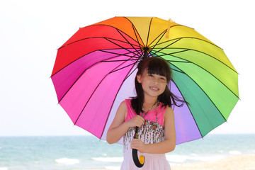 Asian young girl on the beach with colorful umbrella in her hand