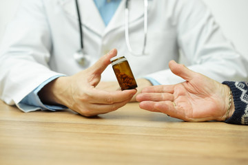 Doctor is  giving bottle of pills  to an  old female  patient