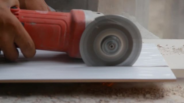 worker cutting a tile using an angle grinder at construction site