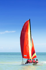 Fototapeta premium Colorful catamaran with four passengers on board heading out to