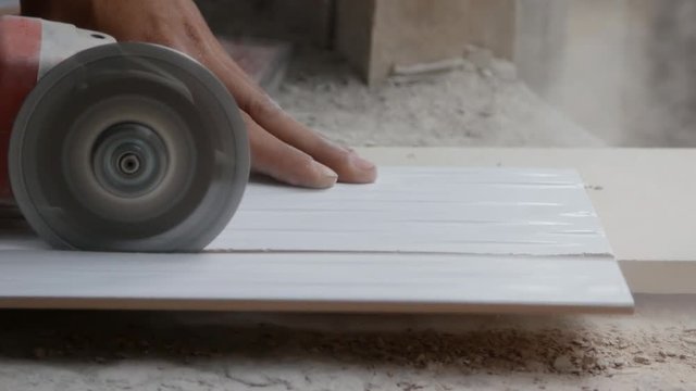 worker cutting a tile using an angle grinder at construction site