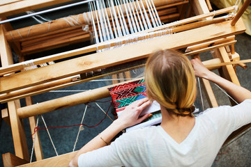 The girl in the production process of textiles are handmade on a loom