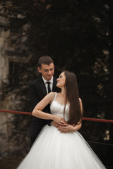 Fototapeta premium Happy wedding couple hugging and smiling each other on the background gorgeous plants in castle