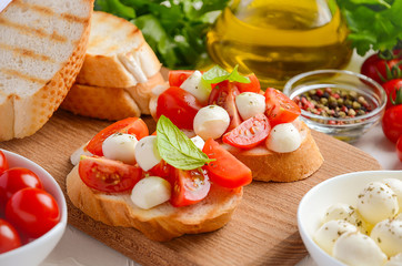 Bruschetta with cherry tomatoes and mozzarella on wooden board.
