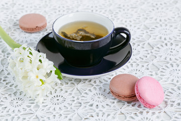 Cup of green tea, color macaroon and white flowers
