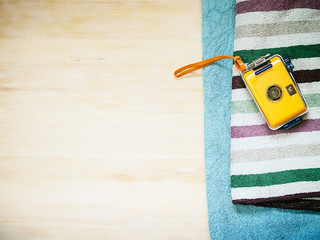 Waterproof camera and towels on a wooden background.