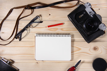 Retro camera with blank notebook on wooden table