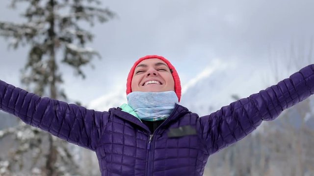 Portrait of happy young woman with outstreched arms in winter mountains