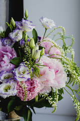 Rich bunch of pink peonies peony and lilac eustoma roses flowers in glass vase on white background. Rustic style, still life. 