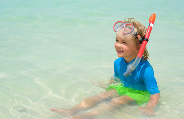 Cute little boy with snorkeling equipment at tropical beach