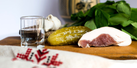 Shot of vodka with pickle, bacon and salad as appetizer on the table