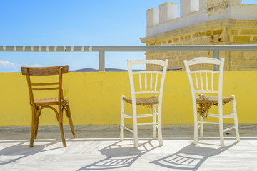 Wooden chairs on a terrace during summer. Bright sunlight and be