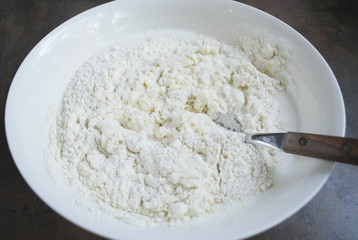Dough for cheesecakes, spoon are in a white dish. Preparation for cooking. 
