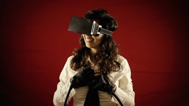 A girl wearing a virtual reality headset and wired gloves, online chatting. Front shot.