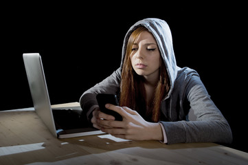 teenager hacker girl in hood using mobile phone in internet cyber crime expert or cybercrime