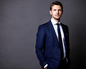 Cool businessman standing on grey 