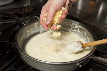 Cheese being added into a hot pan, to melt in preparation for Macaroni cheese