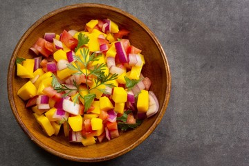 Homemade Mango salsa served in a wooden plate top view