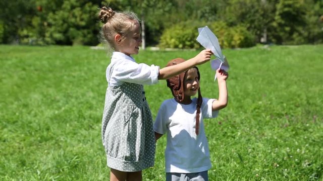Happy children playing with paper planes outdoors. Brother and sister.