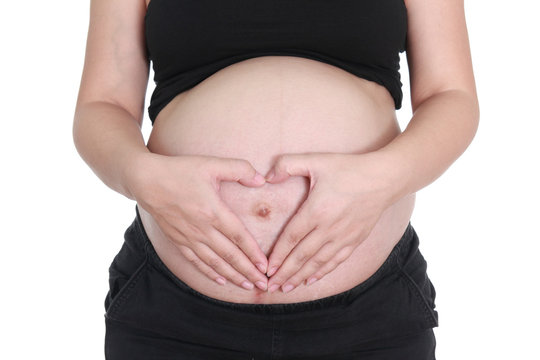 pregnant woman caressing her belly with hand heart sign on white background