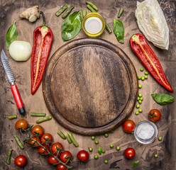 Ingredients for cooking vegetarian food bell peppers, knife for vegetables, cherry tomatoes on a branch and seasoning herbs place for text,frame on wooden rustic background top view 