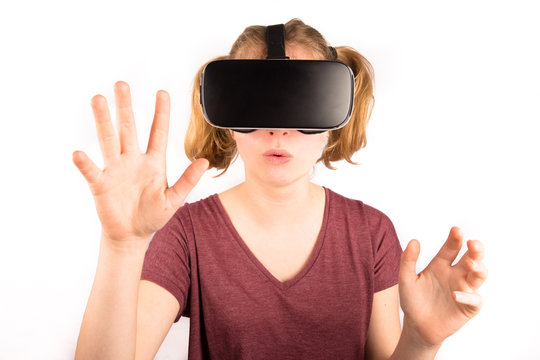 Une jeune fille avec des lunettes de r&eacute;alit&eacute; virtuelle sur fond blanc,de face, tendant les mains devant elle